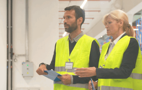 Team of auditors in high-visibility vests conducting a warehouse inspection – business excellence, quality control, and operational assessment.