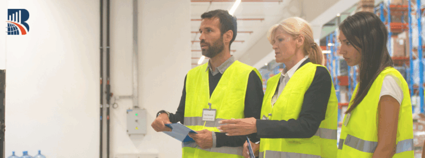 Team of auditors in high-visibility vests conducting a warehouse inspection – business excellence, quality control, and operational assessment.