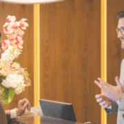 Hotel receptionist assisting a guest at the front desk, representing hospitality and guest experience.
