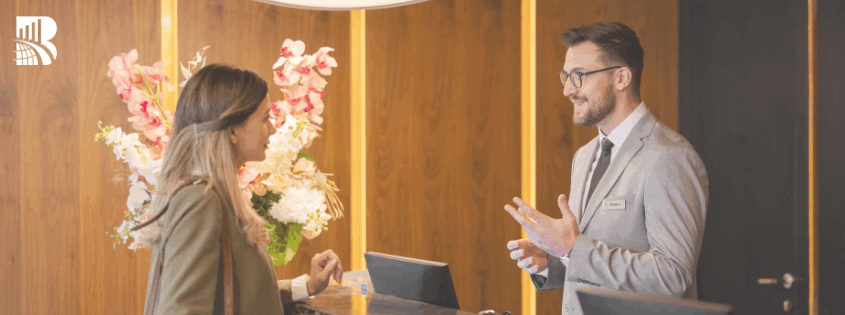 Hotel receptionist assisting a guest at the front desk, representing hospitality and guest experience.