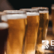 Close-up of beer glasses on a bar counter with the BARE International logo – representing quality evaluation, customer experience, and hospitality insights.