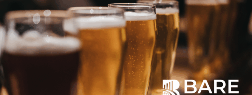 Close-up of beer glasses on a bar counter with the BARE International logo – representing quality evaluation, customer experience, and hospitality insights.