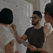 Team in a meeting discussing strategies at a whiteboard – leadership, planning, and innovation at BARE International.