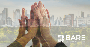 Hands coming together over a city skyline symbolizing ESG-driven customer experience, sustainability, and responsible business growth.