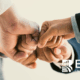 Close-up of professionals joining fists in a teamwork gesture, symbolizing ethics, collaboration, and social responsibility, with the BARE International logo.