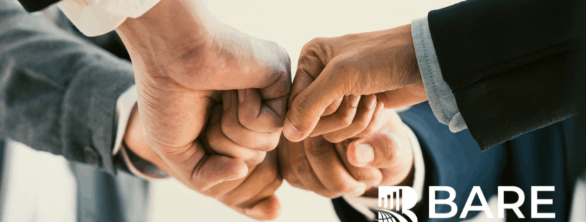 Close-up of professionals joining fists in a teamwork gesture, symbolizing ethics, collaboration, and social responsibility, with the BARE International logo.