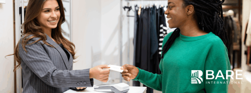 Retail associate assisting a customer at checkout, illustrating consistent in-store customer experience measured through monthly mystery shopping